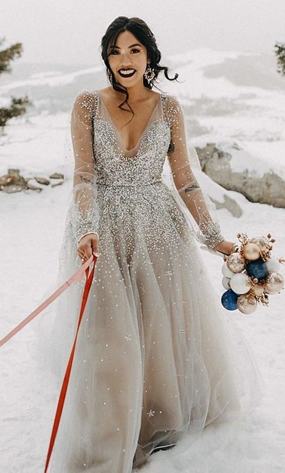 a silver wedding ballgown with a depe neckline, long sleeves and statement snowflake earrings for a winter bride