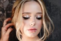 a very fresh and shiny holiday wedding makeup with a glossy nude lip, silver eyeshadow, fresh tone and a touch of blush