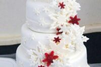 a white wedding cake decorated with red and white snowflakes and topped with them is a lovely idea for a winter wedding