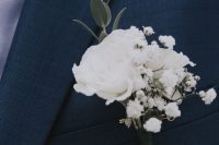 a white winter wedding boutonniere of blooms and a leaf branch is a delicate and chic accessory to rock