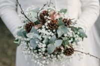 a winter wedding bouquet of greenery, baby’s breath, pinecones and twigs plus some ribbon is amagical idea for winter