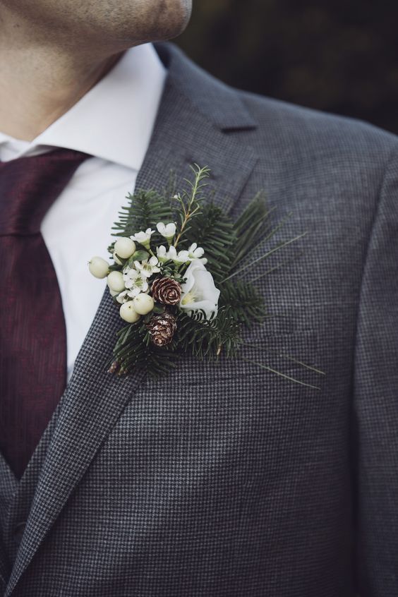 a winter wedding boutonniere of berries, pinecones, white blooms and greenery for a rustic touch