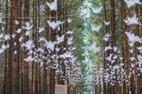 a woodland wedding ceremony space with lots of paper cranes and wooden trunks