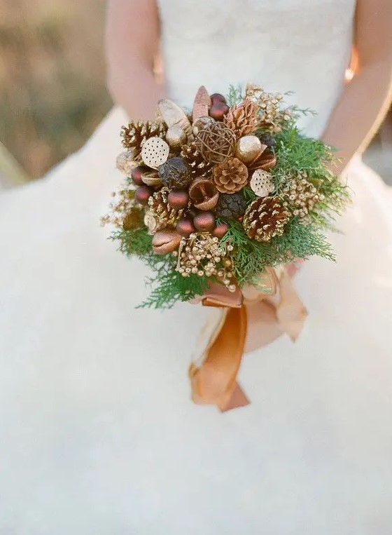 a woodsy-inspired bouquet with gilded pinecones, ornaments, berries, nuts, fern and a camel ribbon