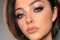 shiny holiday makeup with a glossy nude lip, silver mtallic eyeshadow, wings and lash extensions