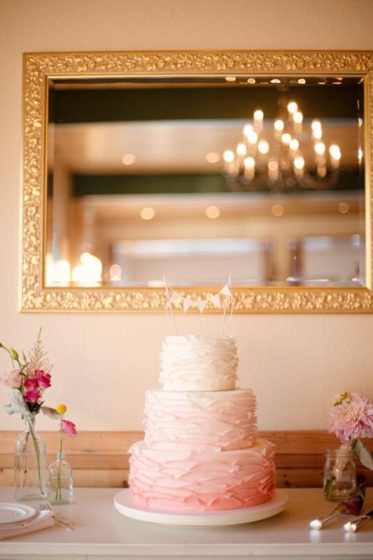An ombre white to pink textural buttercream wedding cake with a banner cake topper is a lovely idea for a spring or summer wedding