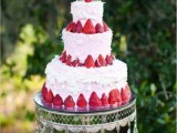 a pink and white buttercream wedding cake with fresh strawberries and bird cake toppers is a gorgeous idea for summer, looks delicious