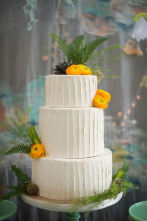a white buttercream wedding cake with greenery, seed pods, yellow blooms and pinecones is a lovely idea for a bold summer wedding