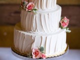 a white textural buttercream wedding cake decorated with white and pink roses and greenery is a chic and elegant idea