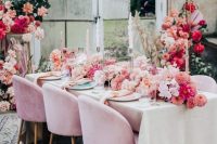 a beautiful and colorful wedding tablescape with peachy, hot pink, blush blooms, pink chairs and napkins and a bold floral arrangement next to the table
