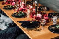 a bold wedding tablescape with black candles and plates, hot red and pink blooms on the table