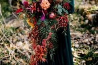 a breathtaking bold fall cascadign wedding bouquet of orange, burgundy, red and yellow blooms, greenery and berries is amazing