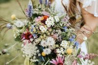 a bright boho summer cascading wedding bouquet of white, pink, yellow, orange blooms, greenery and textural touches