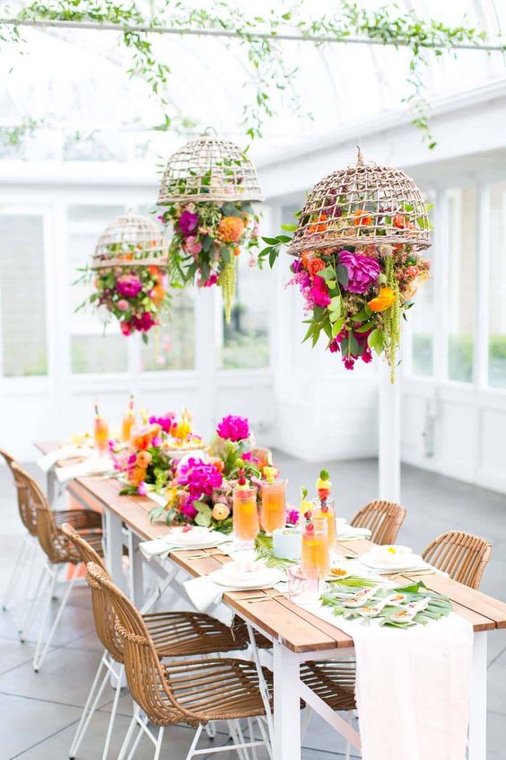 a bright wedding table setting with hot pink, orange and yellow blooms, greenery, tropical leaves and neutral linens is a lovely idea