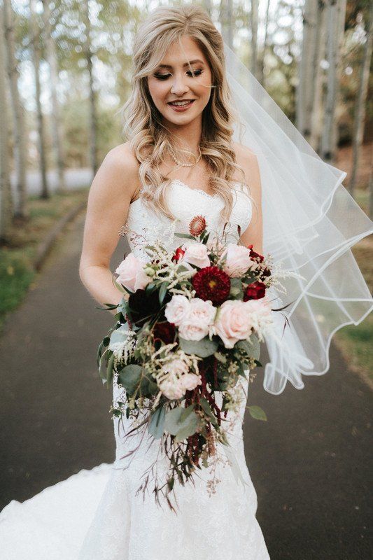a cascading wedding bouquet of blush, burgundy and deep purple blooms plus greenery is a gorgeous idea for a summer or fall bride