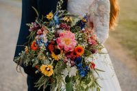 a colorful cascading wedding bouquet with yellow, orange, pink and blue flowers, greenery is a bold idea for a summer wedding with lots of color