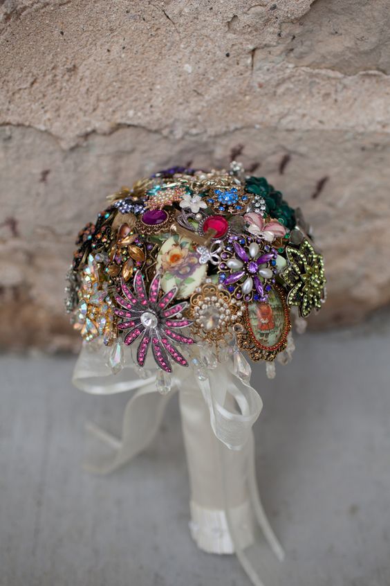 a colorful vintage brooch wedding bouquet with a tulle wrap with a bow is a chic and nice idea for a bright wedding