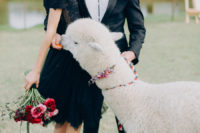 a couple wearing black, a hot red and pink wedding bouquet and a matching boutonniere