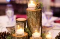 a cozy rustic centerpiece of evergreens, pinecones, candles on tree stumps for a cozy rustic winter wedding