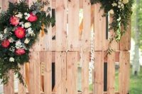 a cute rustic wedding ceremony or sweetheart table backdrop made of pallets and lush florals and greenery