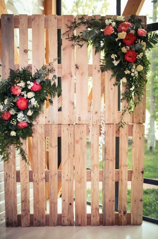 a cute rustic wedding ceremony or sweetheart table backdrop made of pallets and lush florals and greenery