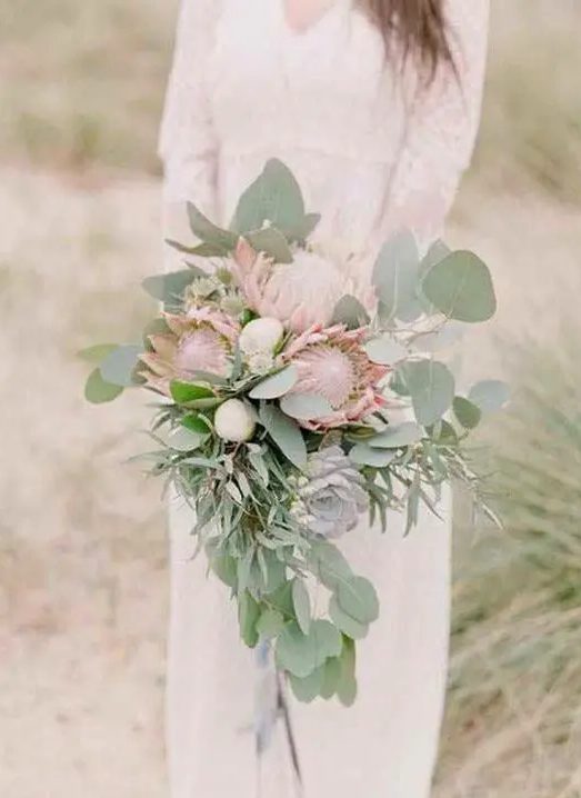 a delicate cascading wedding bouquet with eulcayptus, king proteas and succulents for a textural and catchy look