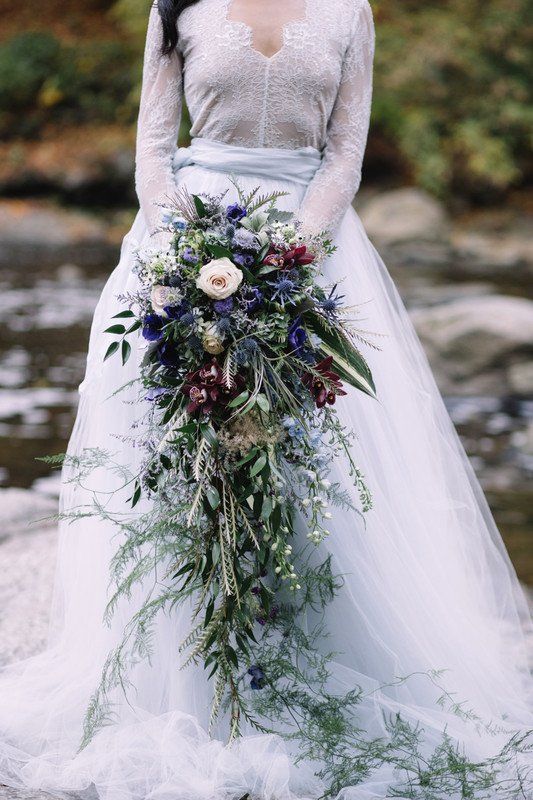 a dreamy cascading wedding bouquet of puroke, burgundy and neutral blooms, thistles and greenery plus berries is amazing for a fall or winter wedding