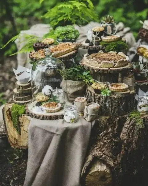 a forest wedding dessert table with lots of tree stumps, slices and delicious pies and tartlets and greenery