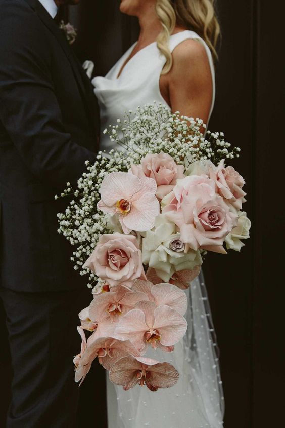 a gorgeous cascading wedding bouquet with blush roses and orchids, white roses and baby's breath is a beautiful idea to rock