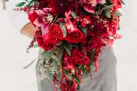 a grey waistcoat and pants, a red printed tie and a lush red and burgundy wedding bouquet with soem foliage