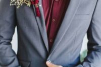 a grey wedding suit with a burgundy shirt and a grey bow tie plus a lush floral boutonniere for a modern groom