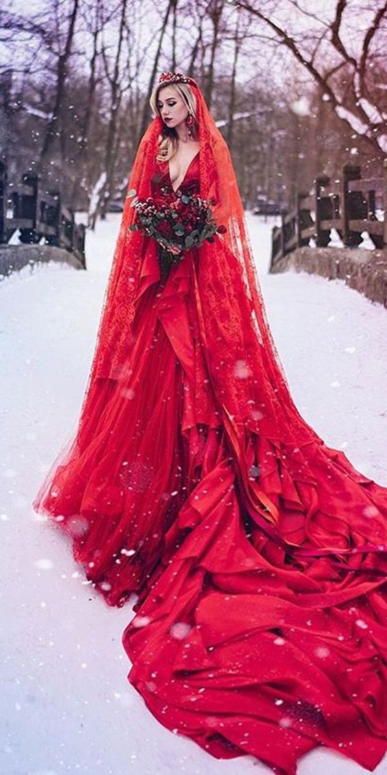 a hot red wedding ballgown with a plunging neckline and a train,, a matching veil and a crown plus a red lip