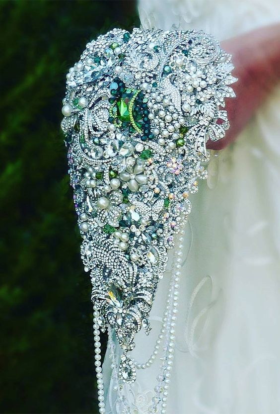 a large cascading silver and green vintage brooch wedding bouquet is a bold statement for a vintage wedding