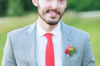 a light grey suit, a red tie and a brigth boutonniere for a bold and chic groom’s look