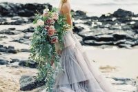 a lush cascading wedding bouquet with much greenery going down, pink and blush blooms for a beautiful coastal bridal look