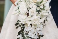 a luxurious cascading white wedding bouquet with roses and peony roses plus some greenery for a refined and glam bride