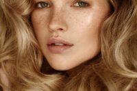 a nude glowy makeup with a shiny nude lip, highlighted eyebrows, highlighter and tone is very chic
