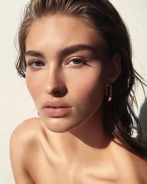 a nude makeup with brushed eyebrows, a touch of mascara, a nude lip and a touch of rouge