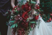 a refined cascading fall wedding bouquet of burgundy roses and peonies, greenery and berries, thistles is a gorgeous idea for a fall bride