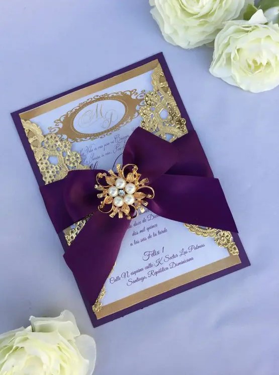 a refined laser cut wedding invitation with laser cut details and a pearl brooch on top