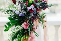 a romantic colorful cascading wedding bouquet with pink, purple and red blooms plus much greenery for a tropical wedding