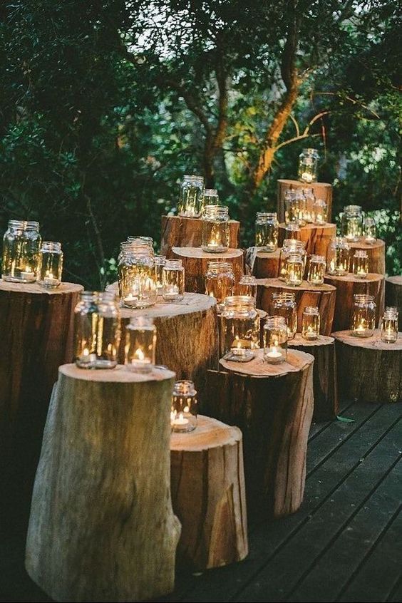 a rustic or woodland wedding altar of multiple tree stumps and candles in jars is a gorgeous idea for a wedding