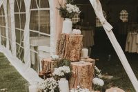 a rustic wedding decoration of tree stumps, white blooms, candles and pumpkins is easy to compose