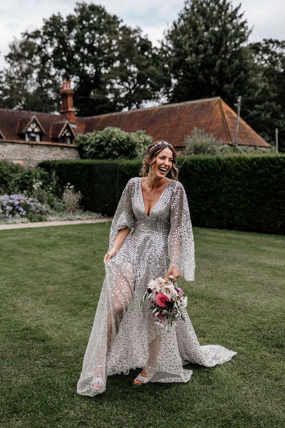 a silver sequin wedding dress with a deep neckline, wide sleeves and sheer parts plus silver shoes