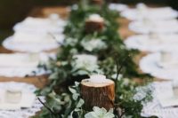 a simple woodland wedding tablescape with a runner made of moss, greenery, succulents and tree branches with candles