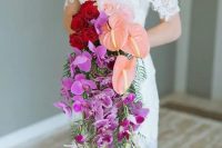 a vibrant cascading wedding bouquet with red roses, pechy callas and hot pink orchids for a bold statement