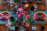 a vibrant wedding tablescape with blue runners, dip dye napkins, hot pink, fuchsia and purple blooms and blue agate stones