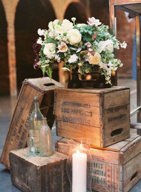 a wedding decoration of crates, bottles, candles and a white floral arrangement is a lovely idea for a laid-back wedding