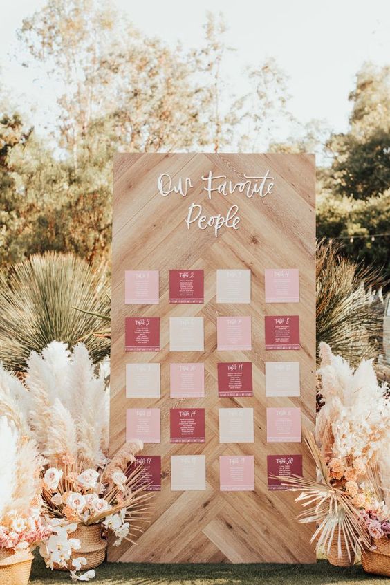 a wedding seating chart of wood, with a seating plan and calligraphy, with super lush florals and grasses around is wow