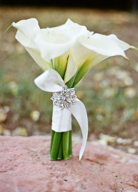 a white calla wedding bouquet with a white ribbon wrap and a vintage boorch is a chic and elegant idea for a wedding
